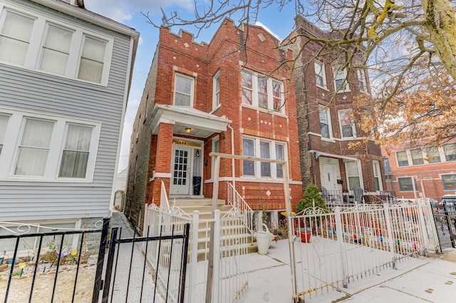 view of front of property featuring a fenced front yard, a gate, and brick siding