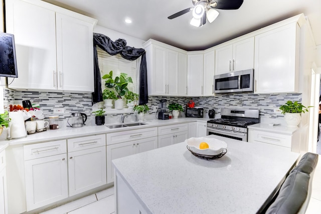 kitchen featuring appliances with stainless steel finishes, a sink, white cabinetry, and decorative backsplash