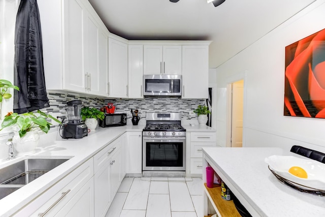 kitchen featuring stainless steel appliances, decorative backsplash, light countertops, and white cabinets