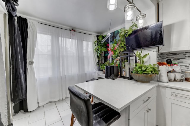 kitchen featuring light tile patterned floors, light countertops, tasteful backsplash, and white cabinetry