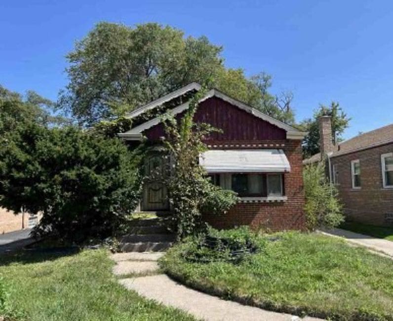 bungalow-style house featuring brick siding and a front lawn