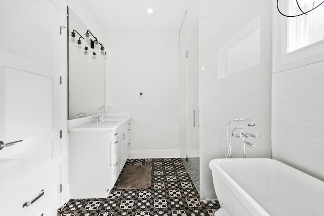 bathroom featuring a soaking tub, baseboards, and vanity