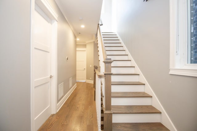 staircase featuring baseboards, wood finished floors, visible vents, and recessed lighting