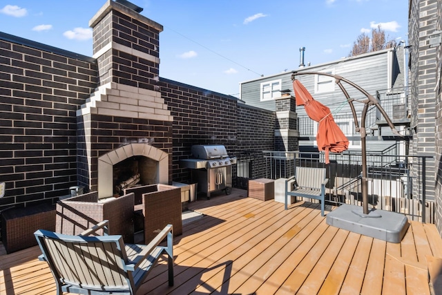 wooden deck featuring an outdoor brick fireplace and grilling area