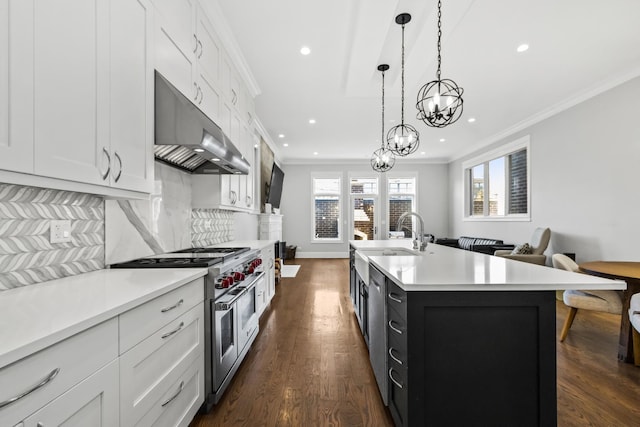 kitchen featuring under cabinet range hood, stainless steel appliances, light countertops, ornamental molding, and tasteful backsplash