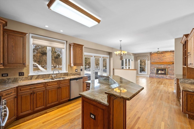 kitchen featuring dishwasher, a fireplace, a kitchen island, and brown cabinets