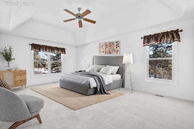 bedroom with light carpet, visible vents, and a tray ceiling