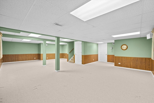 finished basement with wainscoting, wood walls, and visible vents