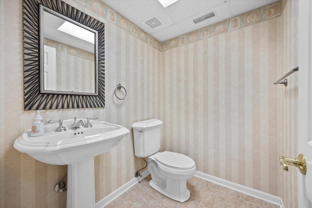 half bath with wallpapered walls, baseboards, visible vents, and tile patterned floors