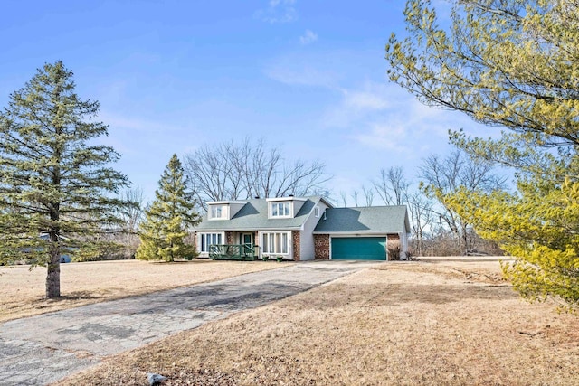 view of front facade featuring driveway, brick siding, and an attached garage