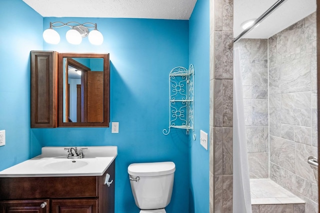 bathroom with tiled shower, vanity, and toilet