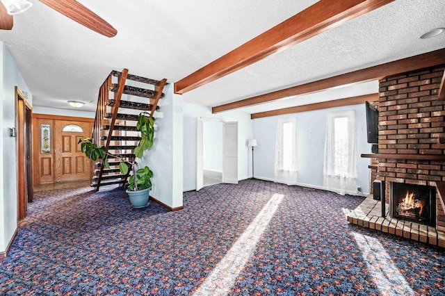 interior space with a fireplace, stairway, a textured ceiling, beamed ceiling, and baseboards