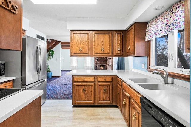 kitchen featuring brown cabinets, light countertops, a sink, and black appliances