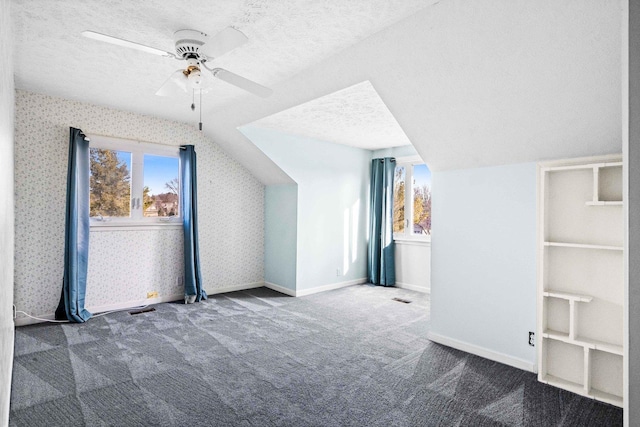 additional living space with a textured ceiling, carpet, lofted ceiling, and wallpapered walls