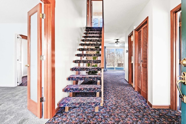 corridor with carpet floors, a textured ceiling, and baseboards