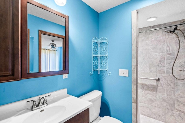 bathroom with toilet, tiled shower, and vanity