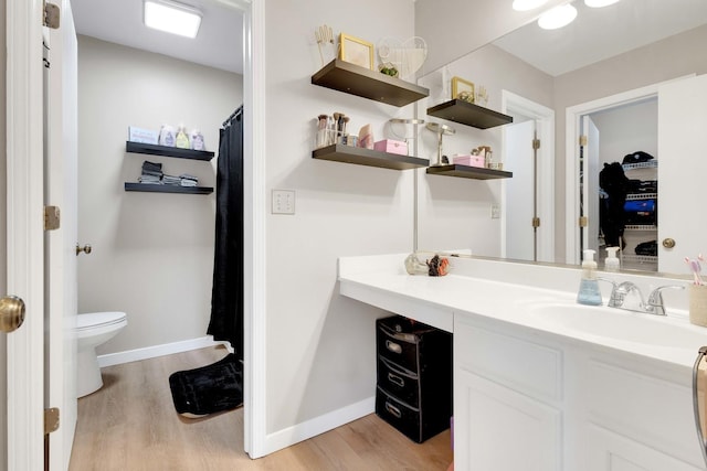 bathroom featuring toilet, wood finished floors, vanity, and baseboards