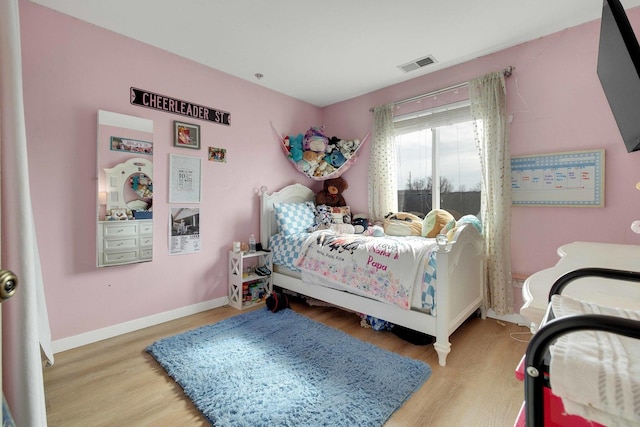 bedroom with light wood-style flooring, visible vents, and baseboards