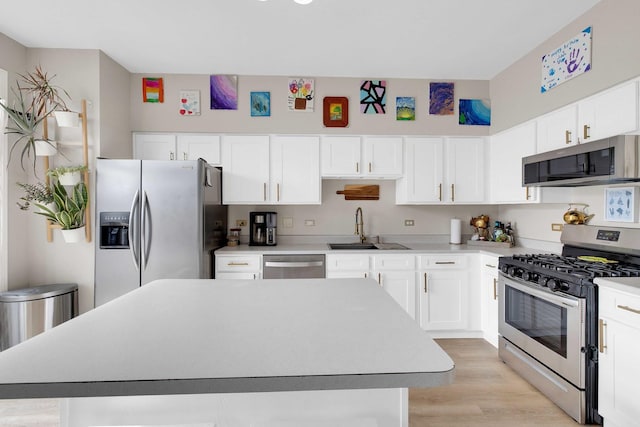 kitchen featuring stainless steel appliances, a center island, light countertops, and a sink