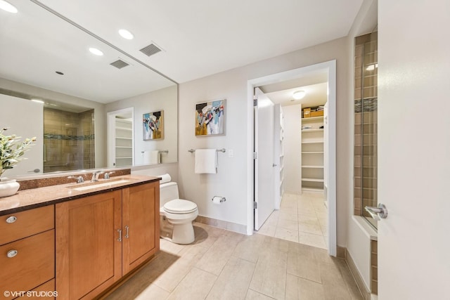 bathroom featuring toilet, vanity, a walk in closet, and visible vents