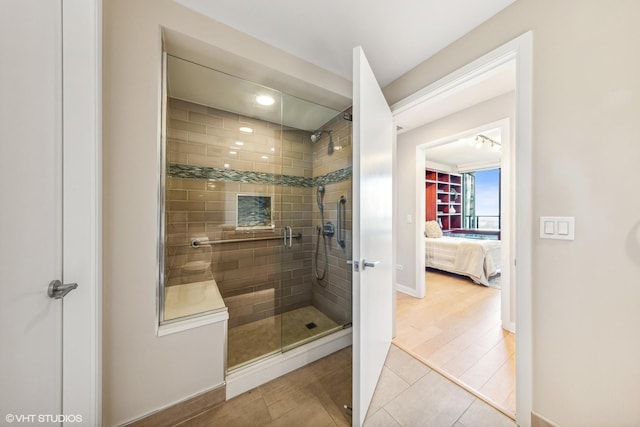 bathroom with a baseboard radiator, a shower stall, ensuite bath, wood finished floors, and baseboards