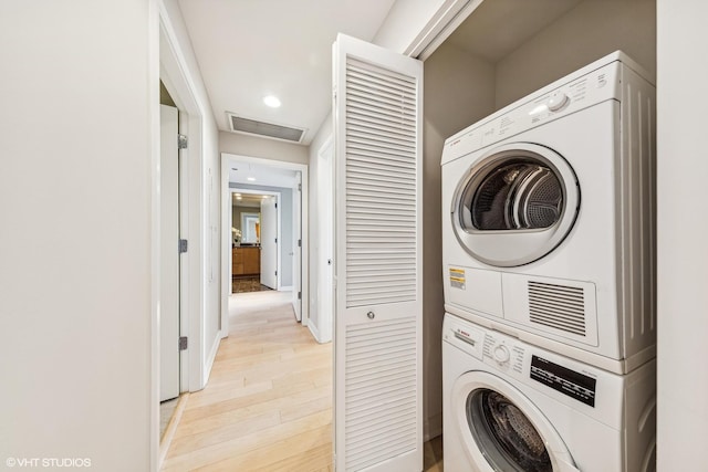 washroom with laundry area, attic access, light wood finished floors, visible vents, and stacked washer and clothes dryer