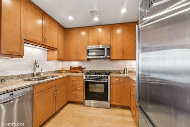 kitchen featuring light stone countertops, appliances with stainless steel finishes, and a sink