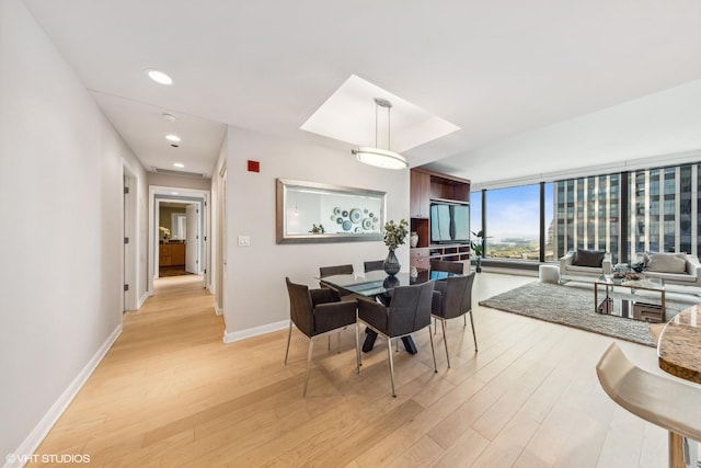 dining room with light wood finished floors, floor to ceiling windows, baseboards, and recessed lighting