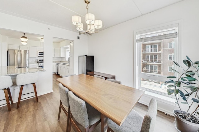 dining area with light wood-style floors, baseboards, and an inviting chandelier