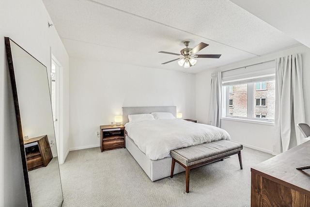 bedroom featuring light carpet, ceiling fan, a textured ceiling, and baseboards