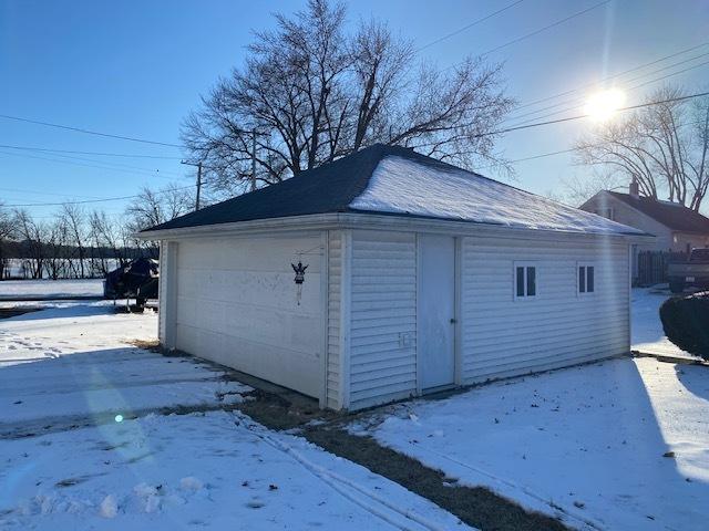 snow covered garage with a detached garage