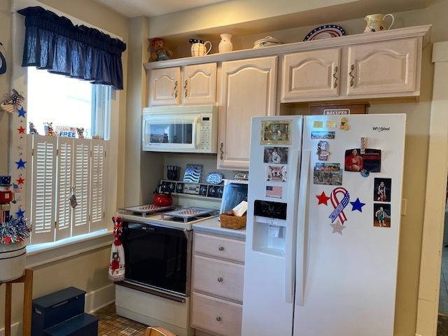 kitchen featuring light countertops, white appliances, and white cabinetry