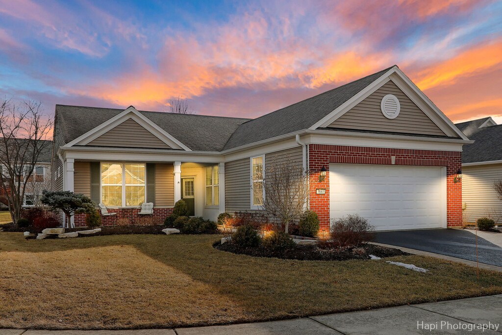 view of front facade featuring driveway, a yard, a garage, and brick siding