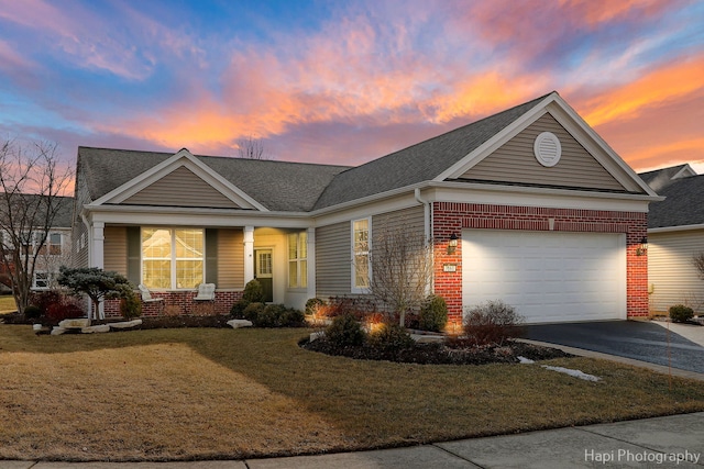 view of front facade featuring driveway, a yard, a garage, and brick siding