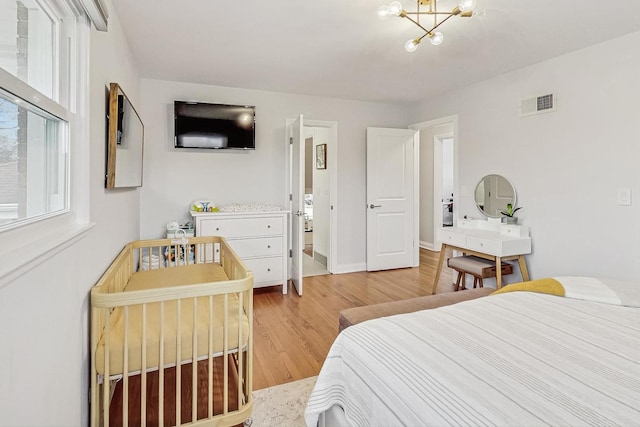 bedroom with a chandelier, baseboards, visible vents, and light wood finished floors