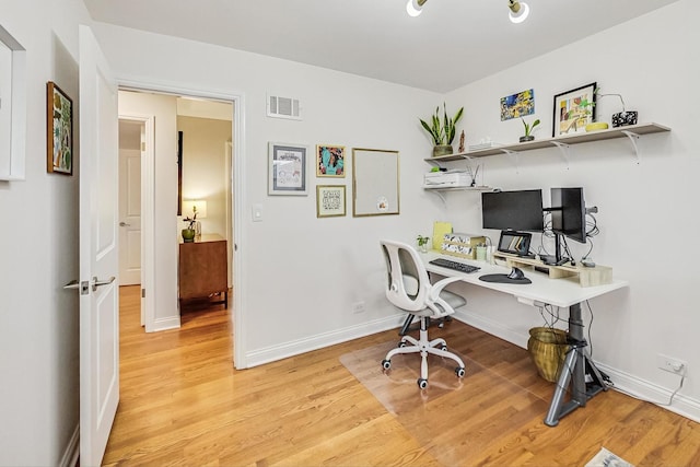 office area with baseboards, visible vents, and wood finished floors