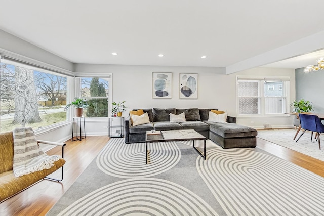 living area with light wood-type flooring, baseboards, a notable chandelier, and recessed lighting