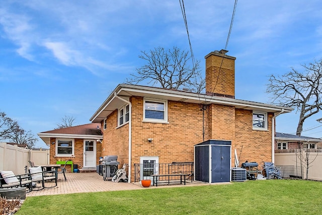 back of property featuring a fenced backyard, cooling unit, a lawn, and brick siding