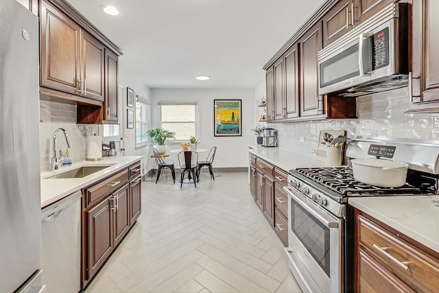 kitchen with tasteful backsplash, recessed lighting, appliances with stainless steel finishes, a sink, and baseboards