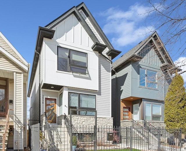 view of front facade featuring a fenced front yard, stone siding, and board and batten siding