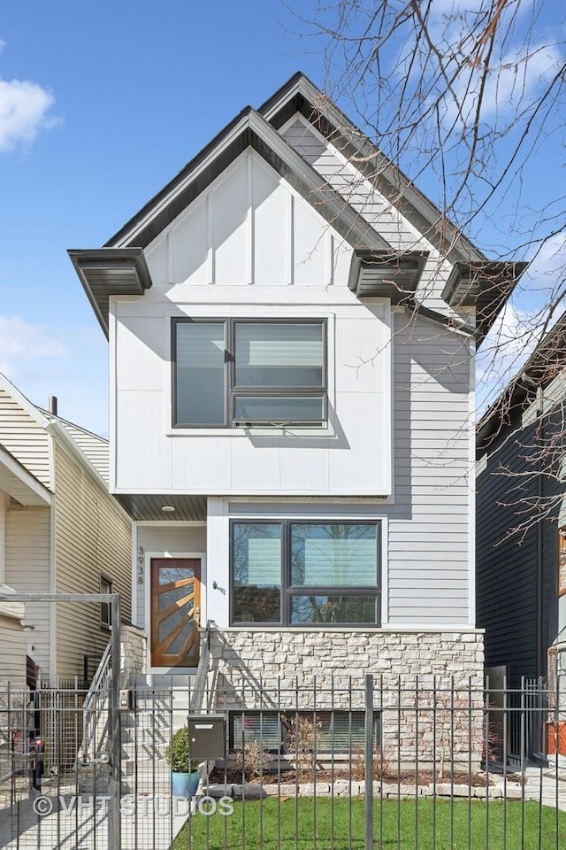 view of front of home with a fenced front yard and stone siding