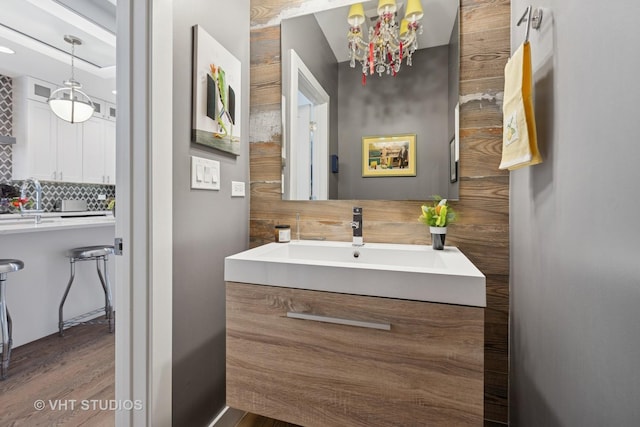 bathroom featuring decorative backsplash, wood finished floors, and a sink