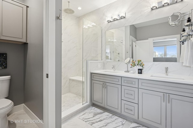 bathroom featuring a sink, a marble finish shower, and toilet