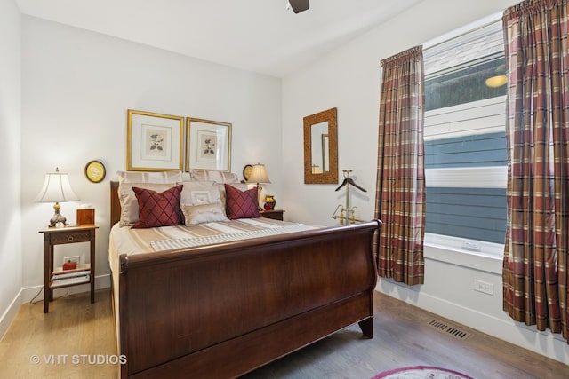 bedroom with visible vents, wood finished floors, baseboards, and ceiling fan