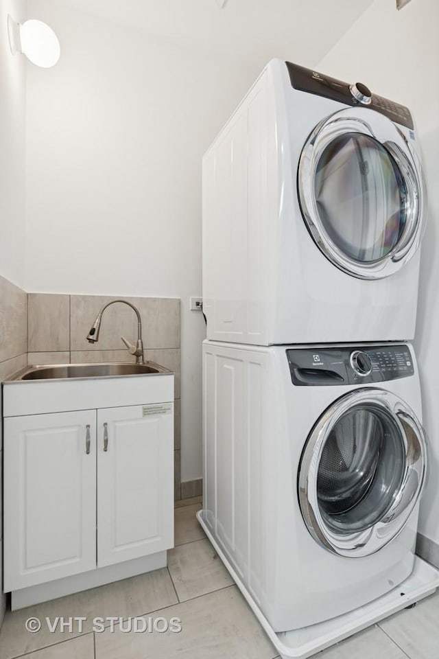 laundry room featuring a sink, stacked washer / drying machine, and cabinet space