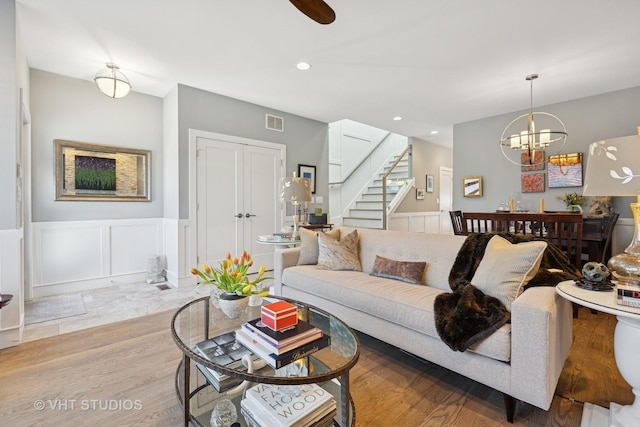 living area with wood finished floors, visible vents, stairs, wainscoting, and a decorative wall