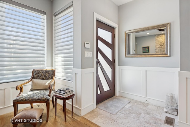 entryway with visible vents, a decorative wall, and a wainscoted wall