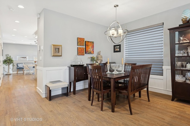 dining area with light wood-style flooring, recessed lighting, wainscoting, a decorative wall, and a chandelier