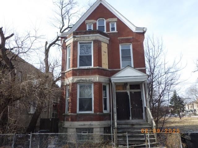 view of front of house featuring entry steps, a fenced front yard, and brick siding