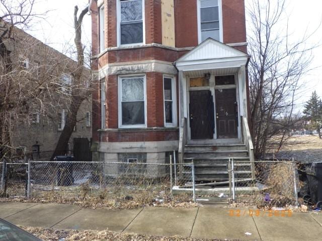 view of front of house with a fenced front yard, entry steps, and brick siding